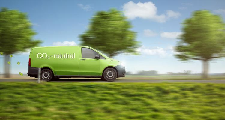 Green car driving in summery landscape.