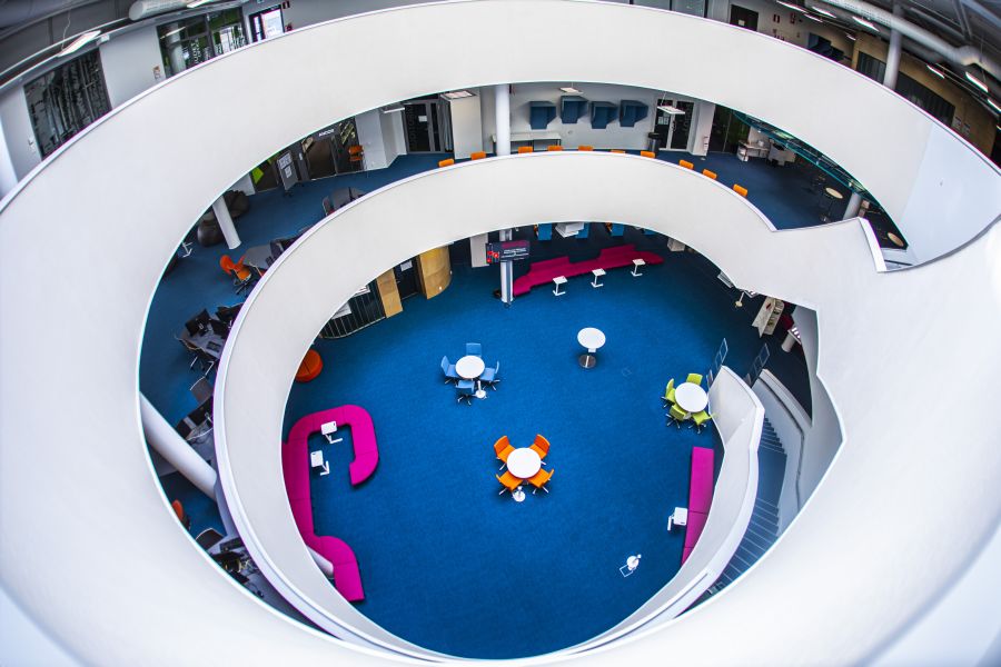 Small desks in the library, stairs leading to the bottom floor.