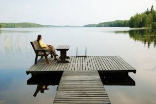 woman sitting on a deck chair at a dock by the lake