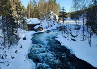 A picture of a river and an old building during winter, with a lot of snow