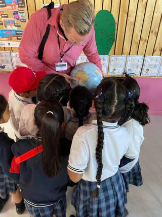 A man holding the globe with children around him.
