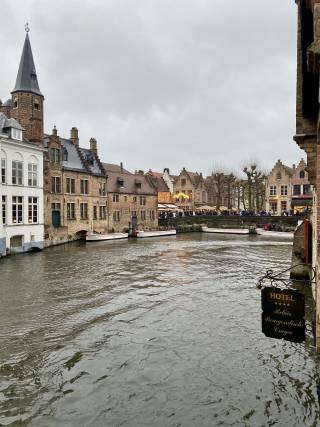 Scenic view of a river in Bruges, Belgium, bordered by elegant buildings, highlighting the city's picturesque landscape.