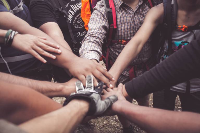 People putting their hands on top of other people's hands in the middle of a circle