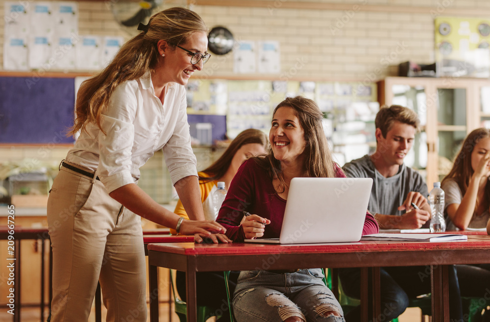 Teacher leaning towards a student who sits.