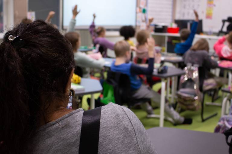 Woman is observing children who sit in a classroom.
