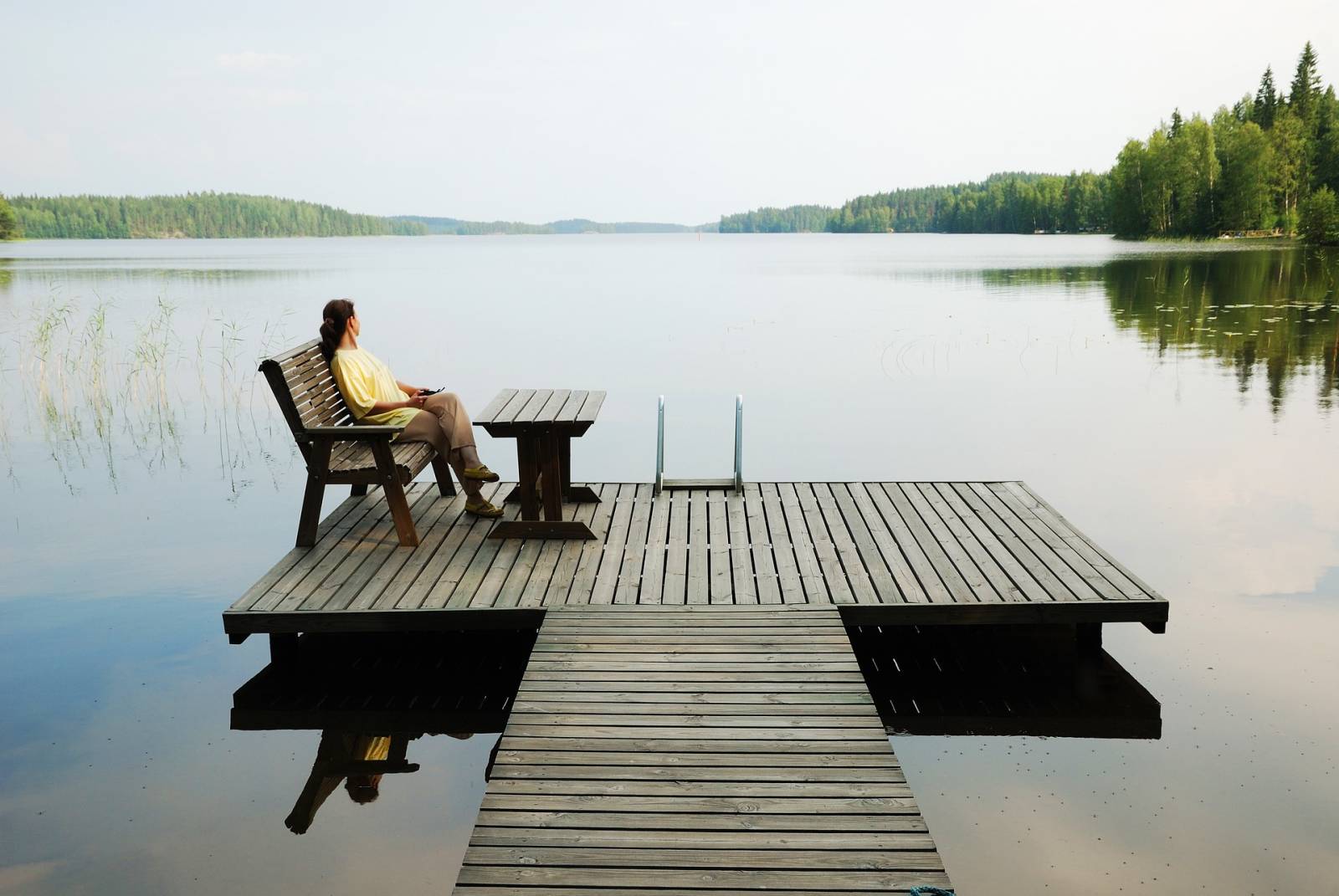 woman sitting on a deck chair at a dock by the lake