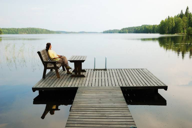 woman sitting on a deck chair at a dock by the lake