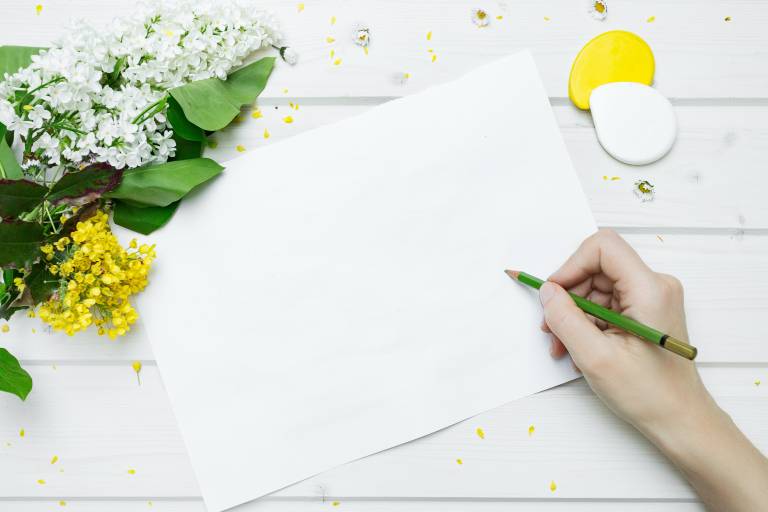 Kuva, jossa käso piirtää kynällä tyhjälle paperille.