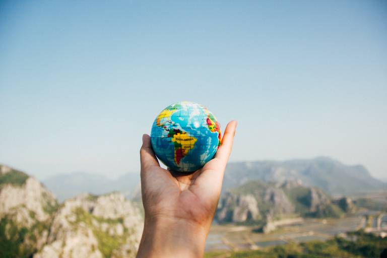 A hand holding a small Earth