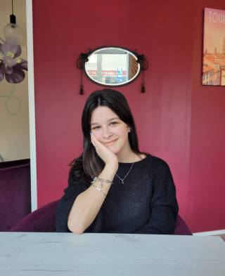 Beatriz sitting at a cafe in front of a red painted door.
