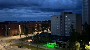 A row of building towards the horizon. The sky is dark and cloudy. Lights stream beautifully in the streets below.