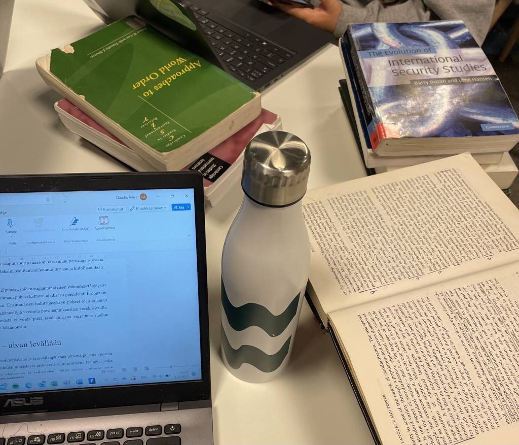 Student studying international relations with books and research materials at Tampere University.