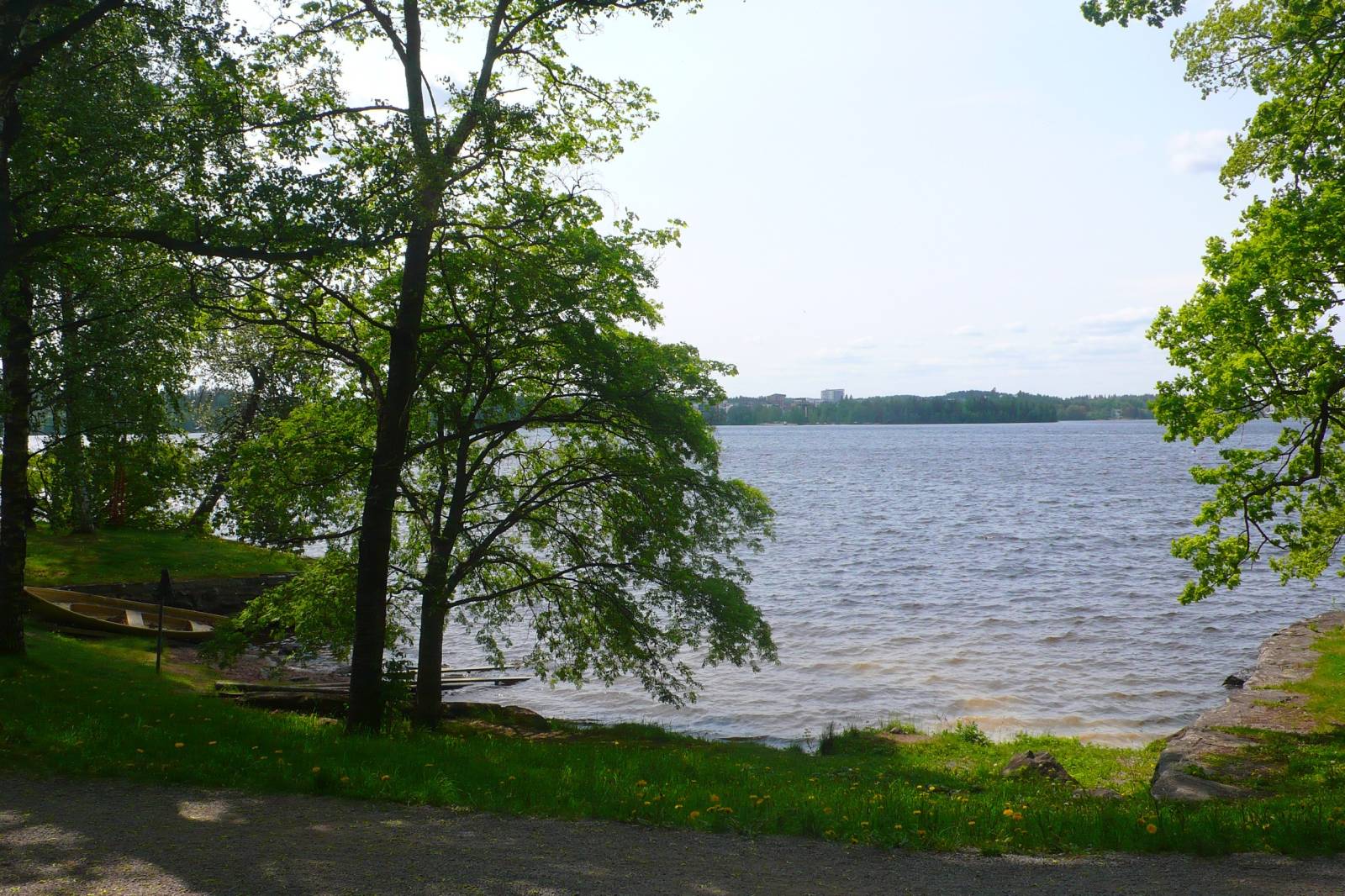 Peaceful lakeside nature view in Finland with calm water and forest surroundings.