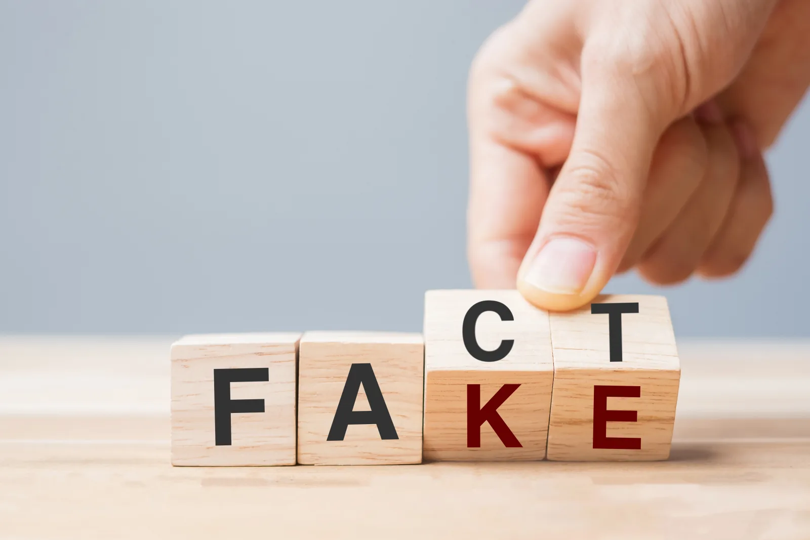 Stock image of Business man hand holding wooden cube with flip over block FAKE to FACT. rumor News, false, myth, evidence and disinformation concepts