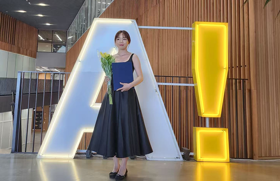 A young woman in a dress holding flowers. 