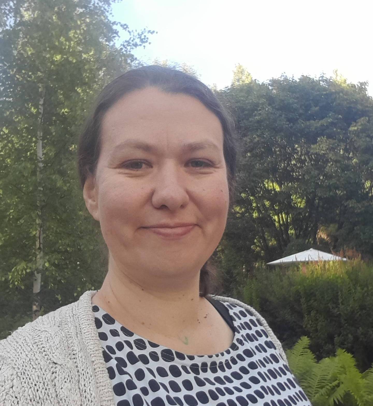 Sirpa hymyilee puistossa.