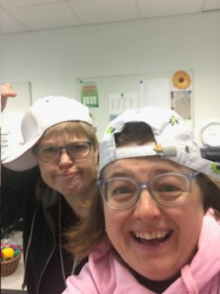 Kaksi hymyilevää ihmistä lippalakit päässä.