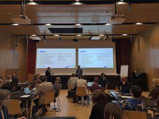 Esitys meneillään. Kuvan etualalla näkyy useita esitystä seuraavia kuuntelijoita selin.