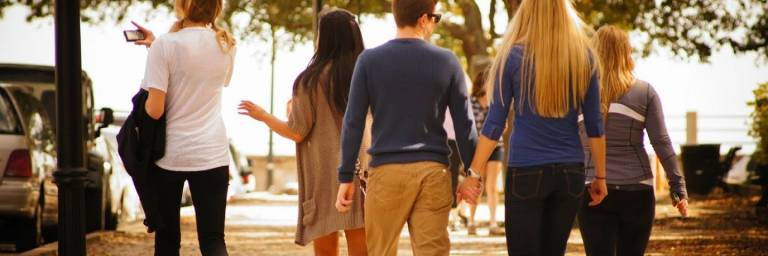 Viisi henkilöä ulkona luonnossa takaapäin kuvattuna,