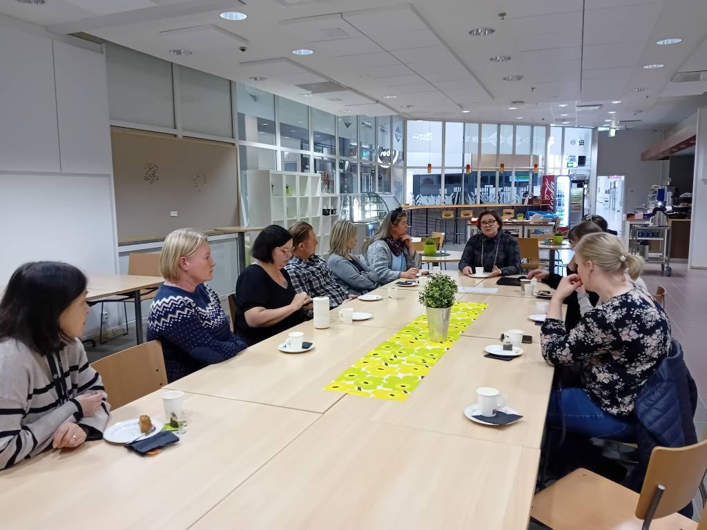 Kymmenen ihmistä kahvipöydän ääressä.