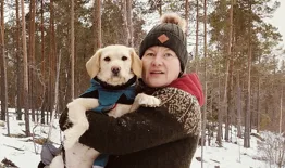 Niina koira sylissään, taustalla metsää.