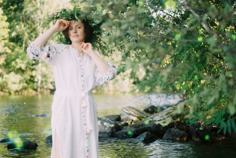 Kuva valkoasuisesta Mariiasta luonnon keskellä.