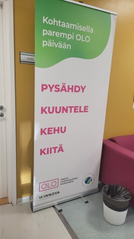 Standi, jossa teksti: "Pysähdy, kuuntele, kehu, kiitä."