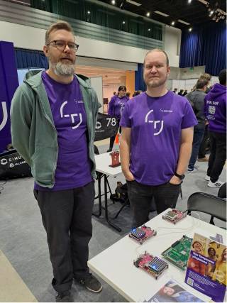 Two men at the fair next to a table with electronics