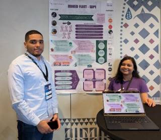 Two persons standing in front of poster