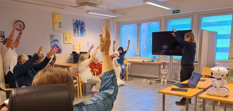 Group of older adults exercising with social robots