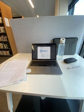 Kuva tietokoneesta ja opiskelutarvikkeista pöydällä.