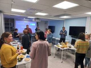 Image shows a group of people mingling and enjoying refreshments