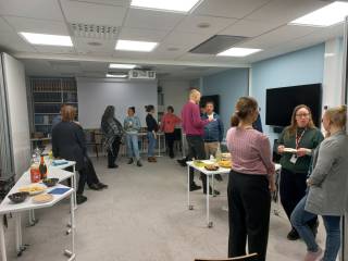 Image shows a group of people mingling and enjoying refreshments after the presentations