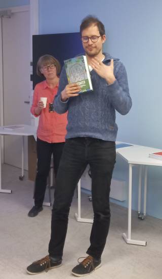 Images shows Professor Riquet standing up and holding the volume The Mediated arctic in his right hand