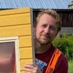 Mies työhaalareissa kurkistaa keltaisen oven takaa.