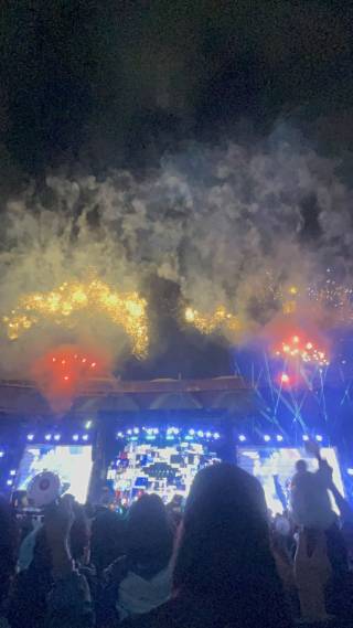 Picture from a concert, displaying large screens and colorful fireworks
