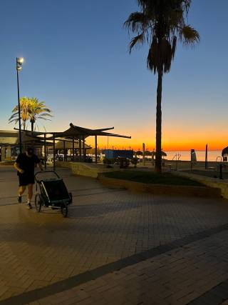 a man runs with a stroller in the morning sun