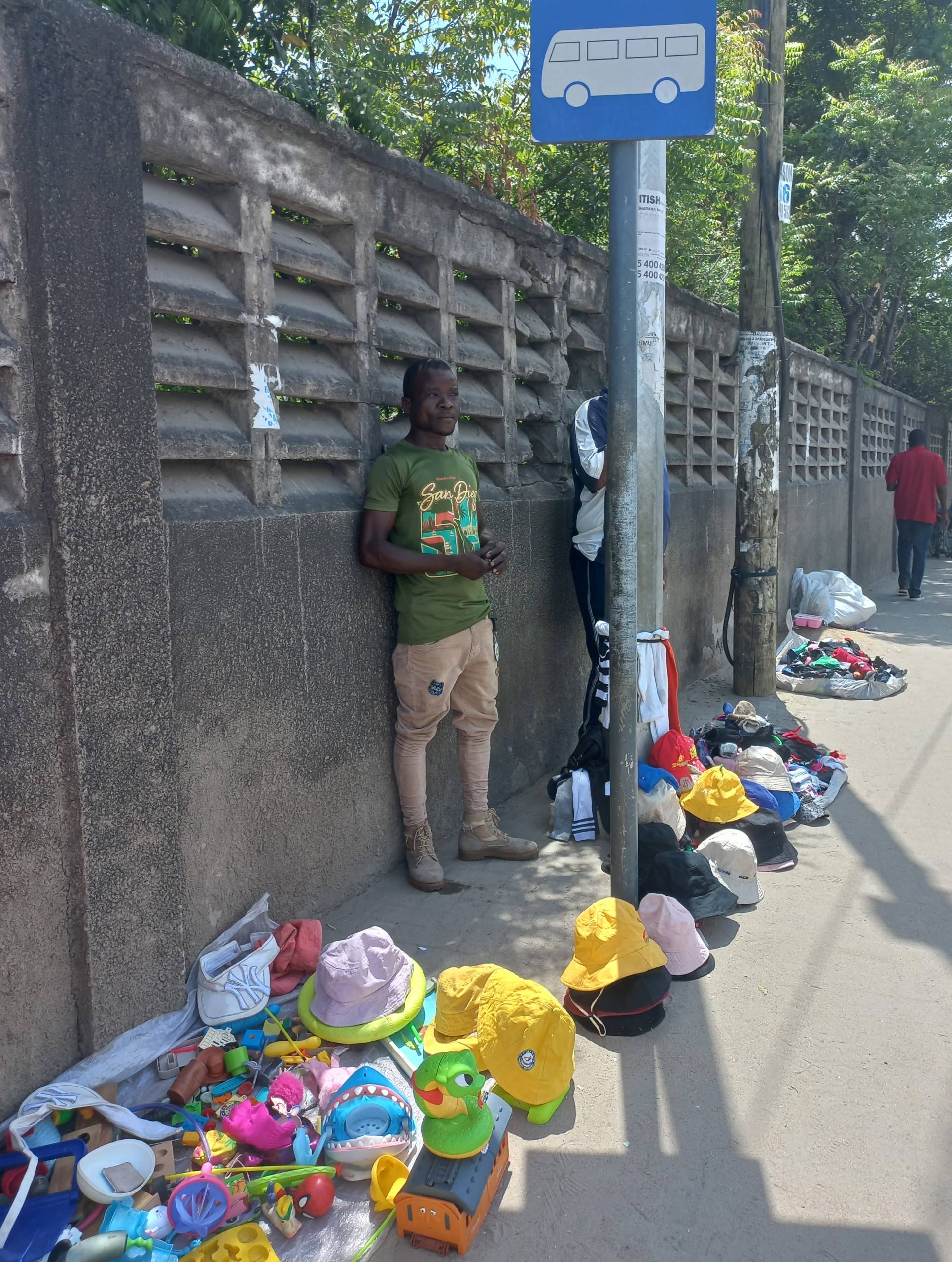 Hawkers peddling clothes and toys on a sidewalk.