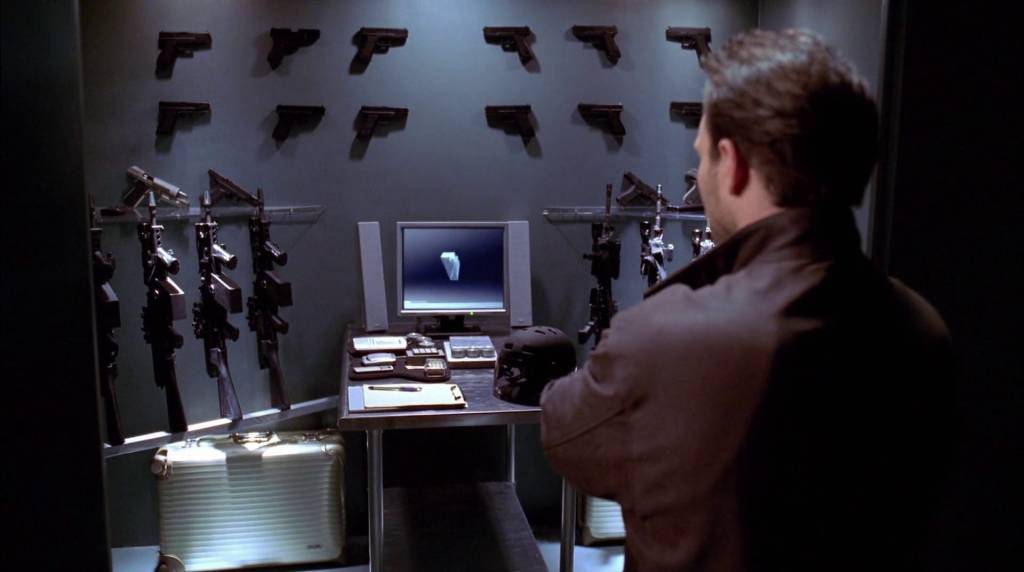 Main character looking at the wall full of guns.