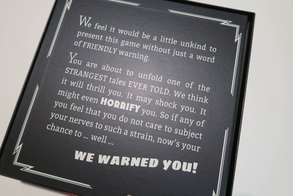 Game box opened. Shows the bottom of the board with a text: "We feel it would be a little unkind to present this game without just a word of FRIENDLY warning." written on it.