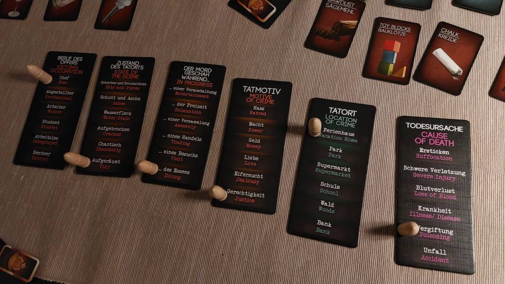 Cardboard tiles displaying various possible contexts about the murder. Their labels read: "Victim's Occupation", "State of the scene", "In progress", "Motive of crime", "Location of crime", and "Cause of death".