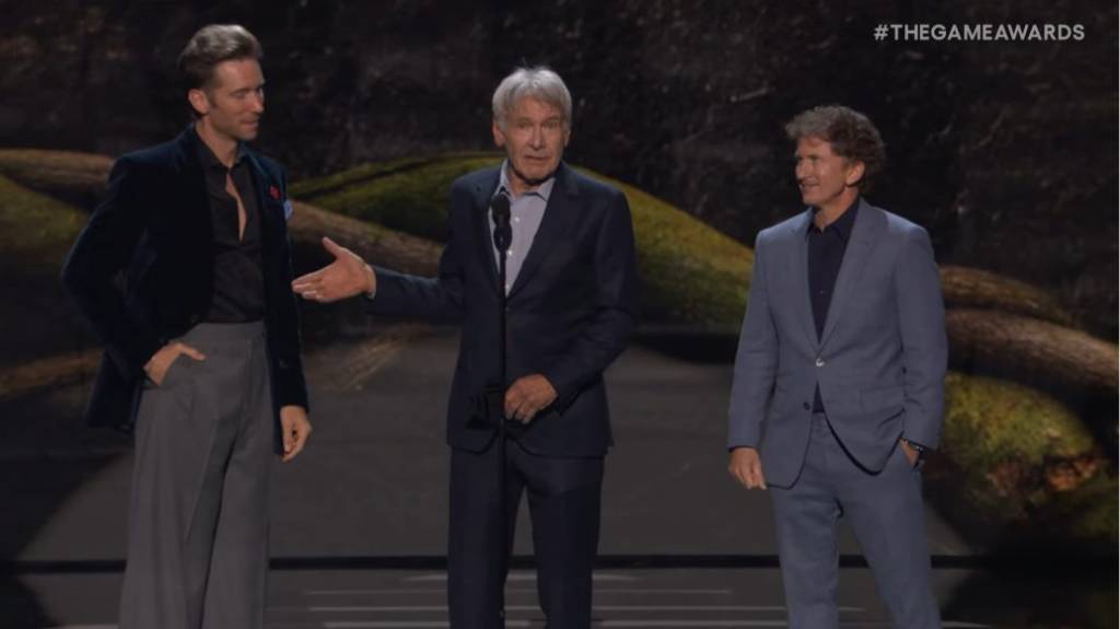 Three men in suits presenting an award on stage.