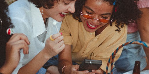 one is playing on gameboy and other is watching her play.