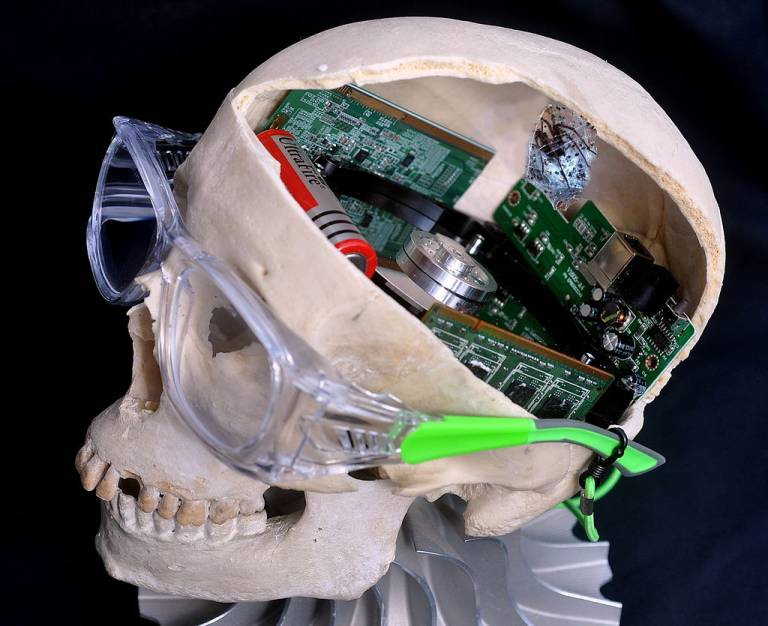 A partly opened human skull with glasses on the face and circuitry inside the cranium.