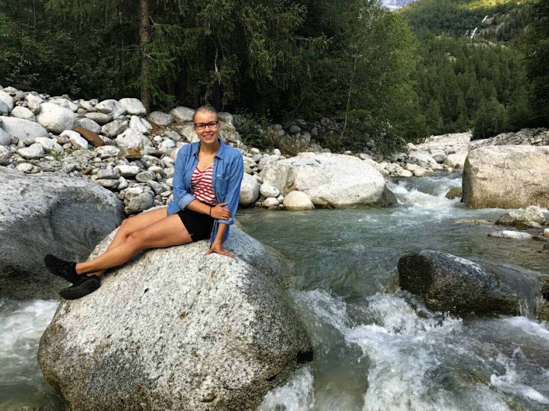 A person sitting on a rock by a river