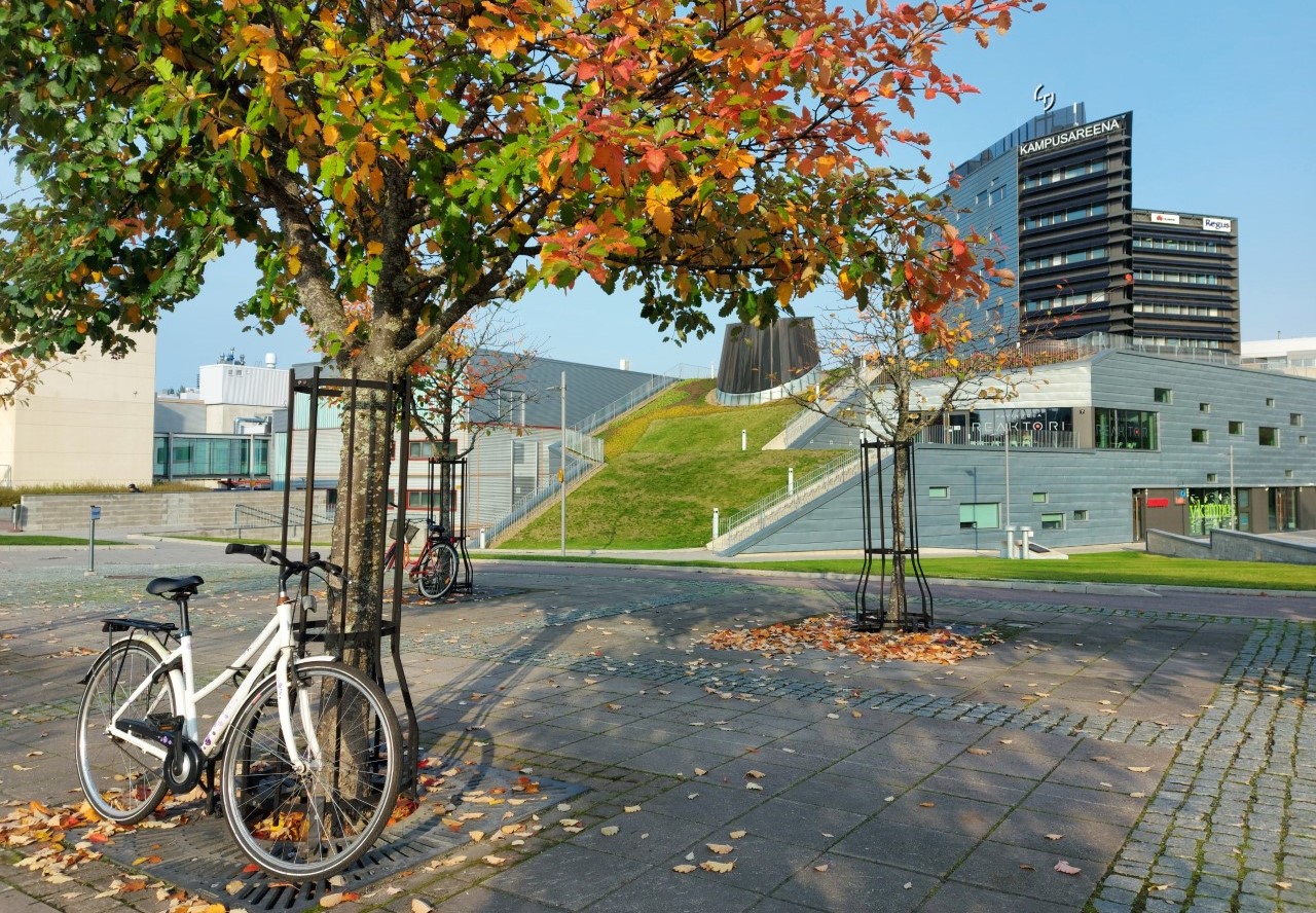 Bike and a colourful tree on Hervanta campus, Kampusareena building in the background.