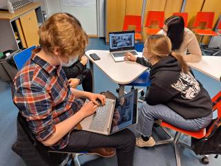 Opiskelijat istuvat pienryhmässä ja suunnittelevat tietokoneilla tilaa