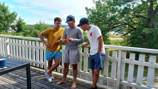three men at a terrace reading a card