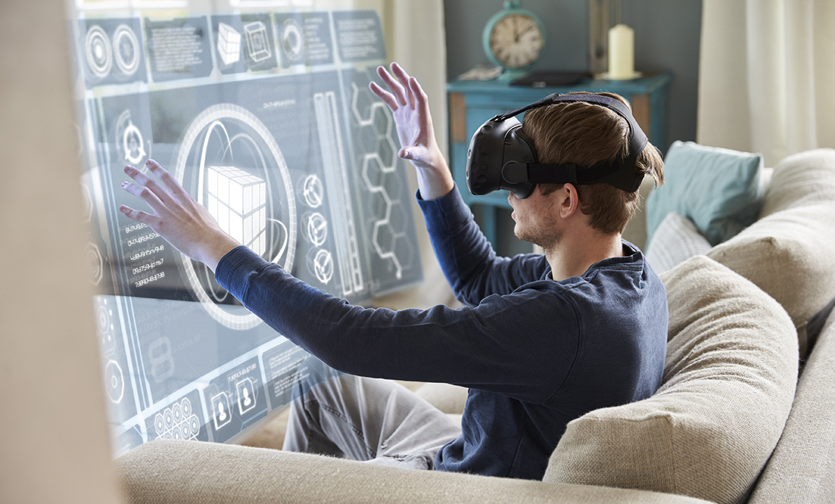 Ihminen istuu sohvalla virtuaalilasit päässään ja tutkii virtuaalista näyttöä.