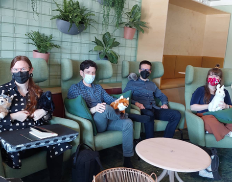 Kuva, jossa hankkeen toimijoita istuu vihreillä sohvatuoleilla Joensuun Tulliportin normaalikoulun virtuaalisessa luokkatilassa pehmolelut sylissään.